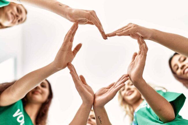 Group of young volunteers woman smiling happy make heart symbol with hands together at charity center. Our 2022 Charity Highlights
